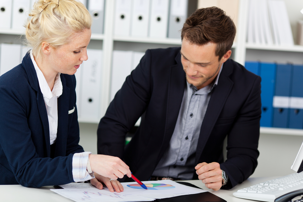 Portrait of a smart young businessteam looking at graphs sitting at office desk